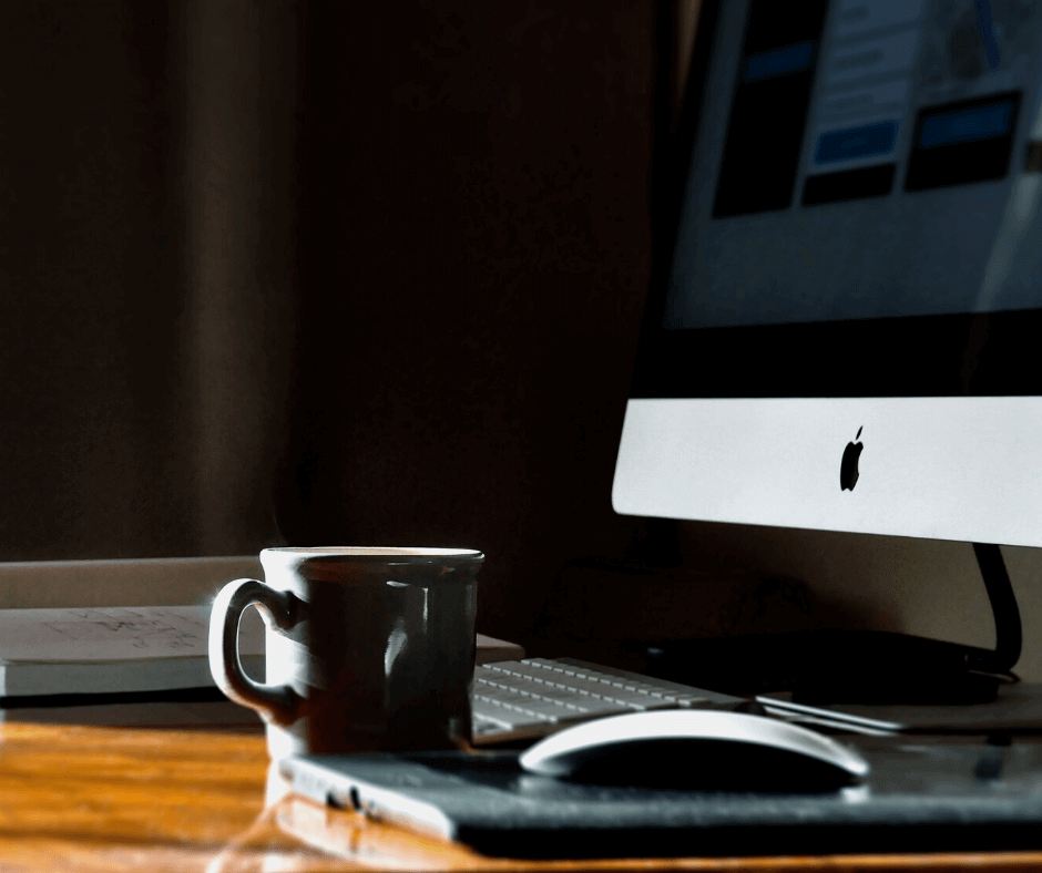 coffee cup next to mac desktop